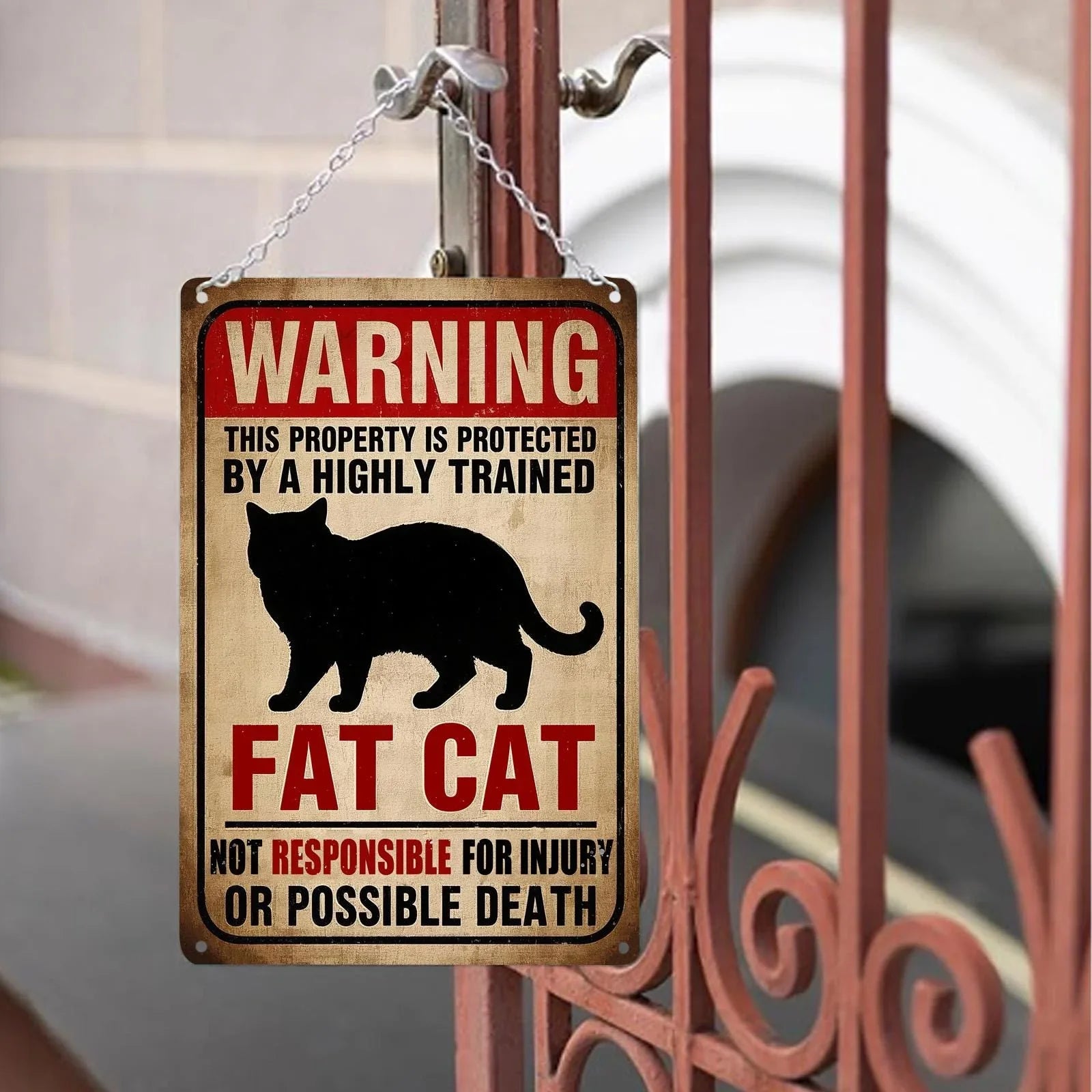 Funny vintage tin sign with warning about a fat cat, hanging on a metal gate outdoors.