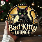 Vintage tin sign featuring black cat, cocktail, and bottles with 'The Bad Kitty Lounge' text.