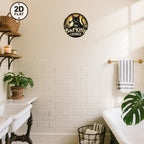 Vintage tin sign with black cat design on bathroom wall, above white subway tiles and bathtub.