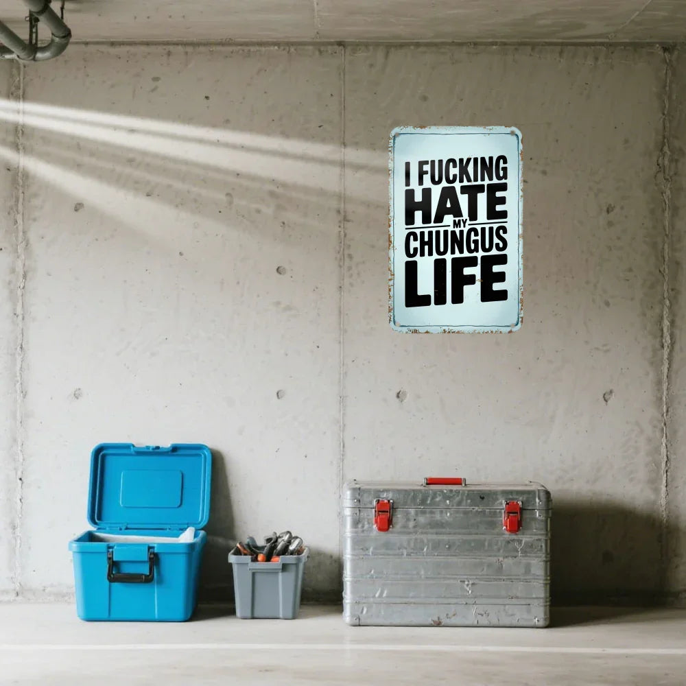 Vintage tin sign with bold humorous quote on a concrete wall above toolboxes in a garage setting.