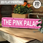 Vintage pink tin sign reading THE PINK PALACE on rustic table with flowers, 2D flat style.