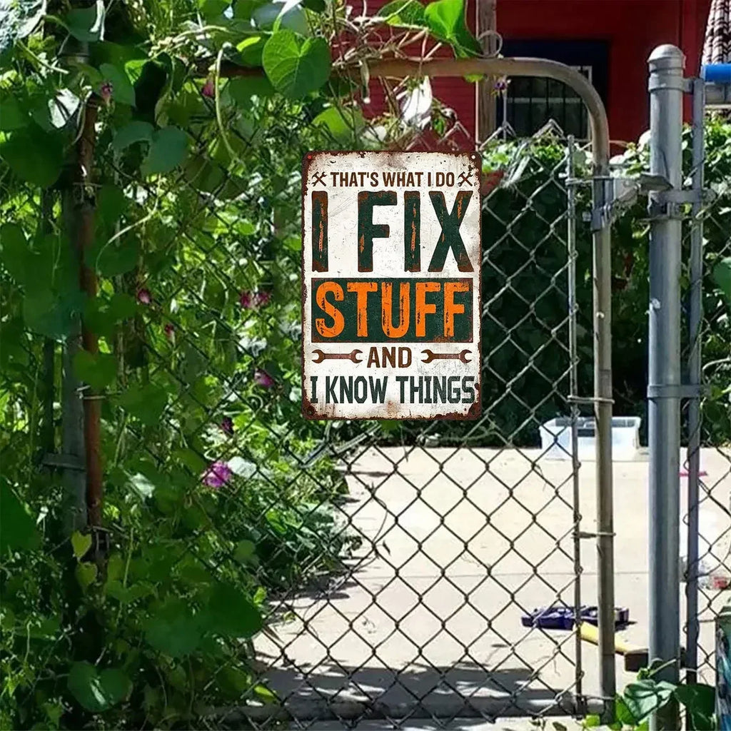 Vintage tin sign on chain link fence reads 'I Fix Stuff and I Know Things', outdoor garden decor.