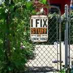 Vintage tin sign on chain link fence reads 'I Fix Stuff and I Know Things', outdoor garden decor.